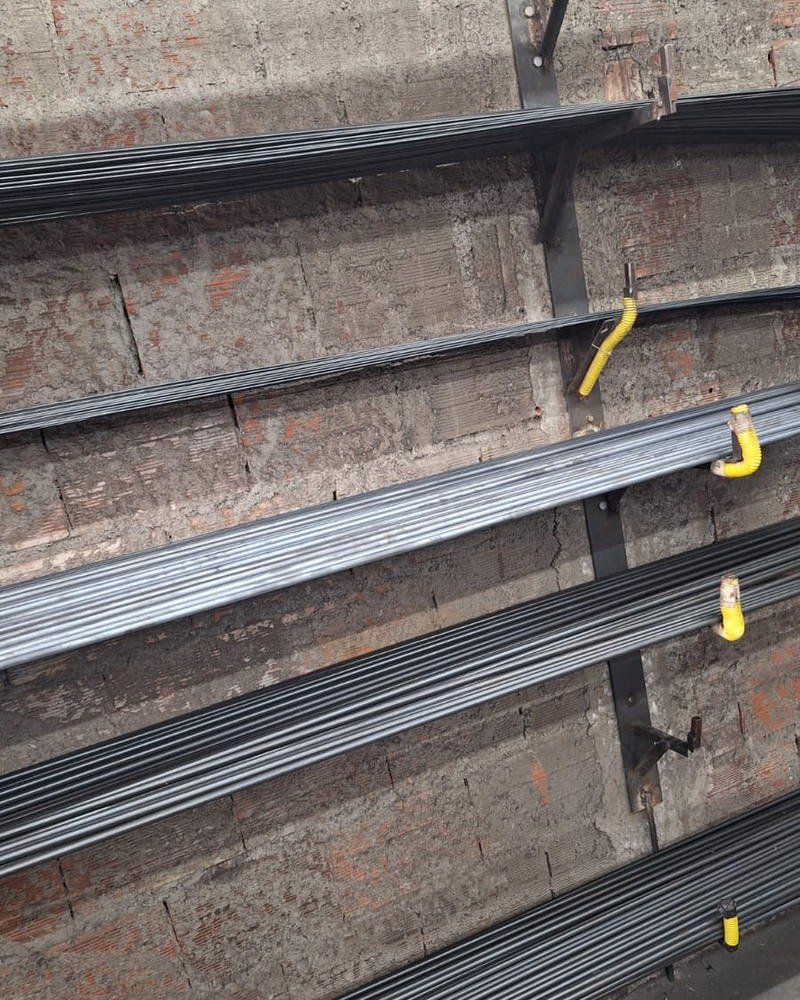 Barras de aço carbono organizadas por bitola no suporte de parede da fábrica da Astro Ferro